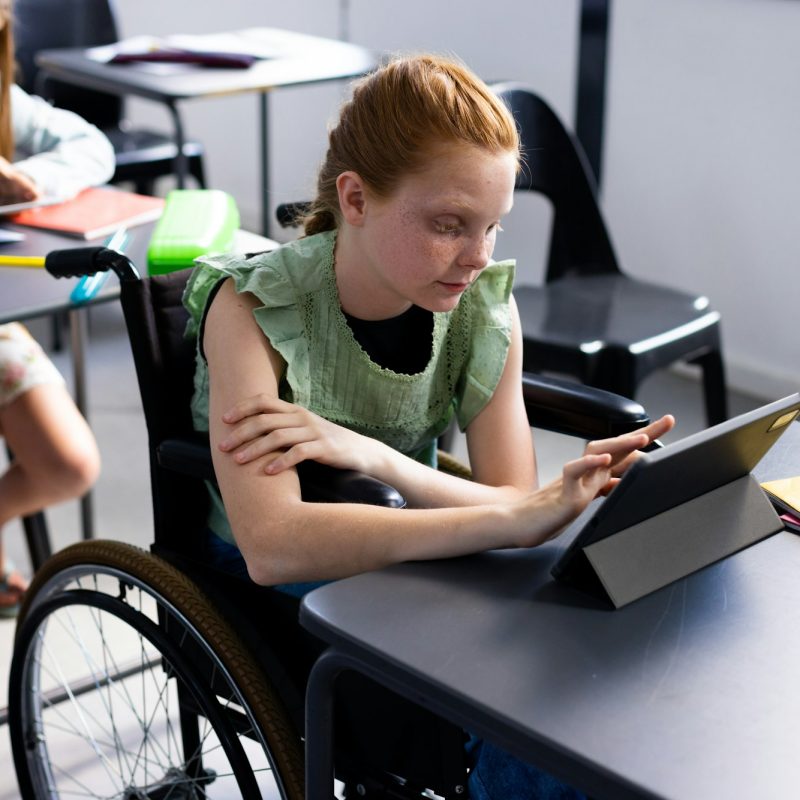 Caucasian schoolgirl in wheelchair with diverse schoolchildren in school classroom