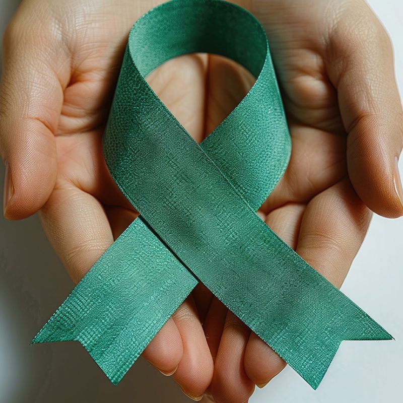 Green handmade awareness paper ribbon on white background.